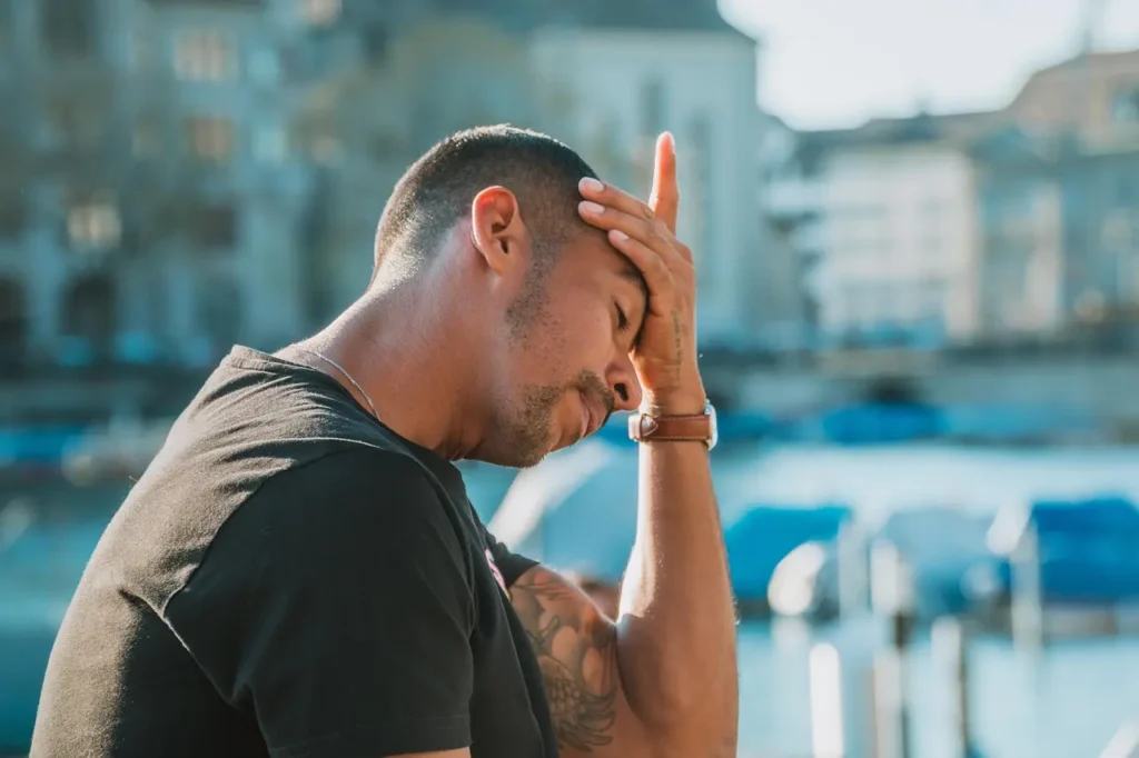 Man leaning on a bridge cradling his head deep in thought and trying to work things out.