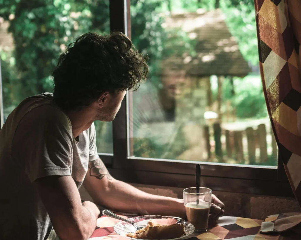 Man looking out of a window reflecting and looking at his image